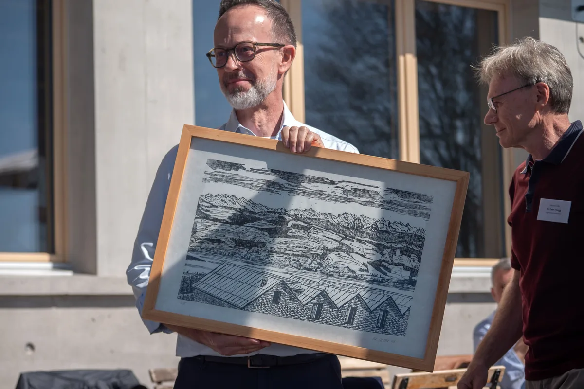Hinwils Gemeindepräsident Andreas Bühler (SP) erhält einen Holzschnittdruck mit dem neuen Bachtel-Restaurant . Hinwils Gemeindepräsident Andreas Bühler (SP) mit einem Bild in den Händen.